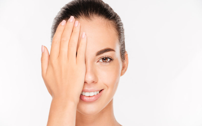 Beauty portrait of a charming woman with skin care covering face with palm isolated on a white background